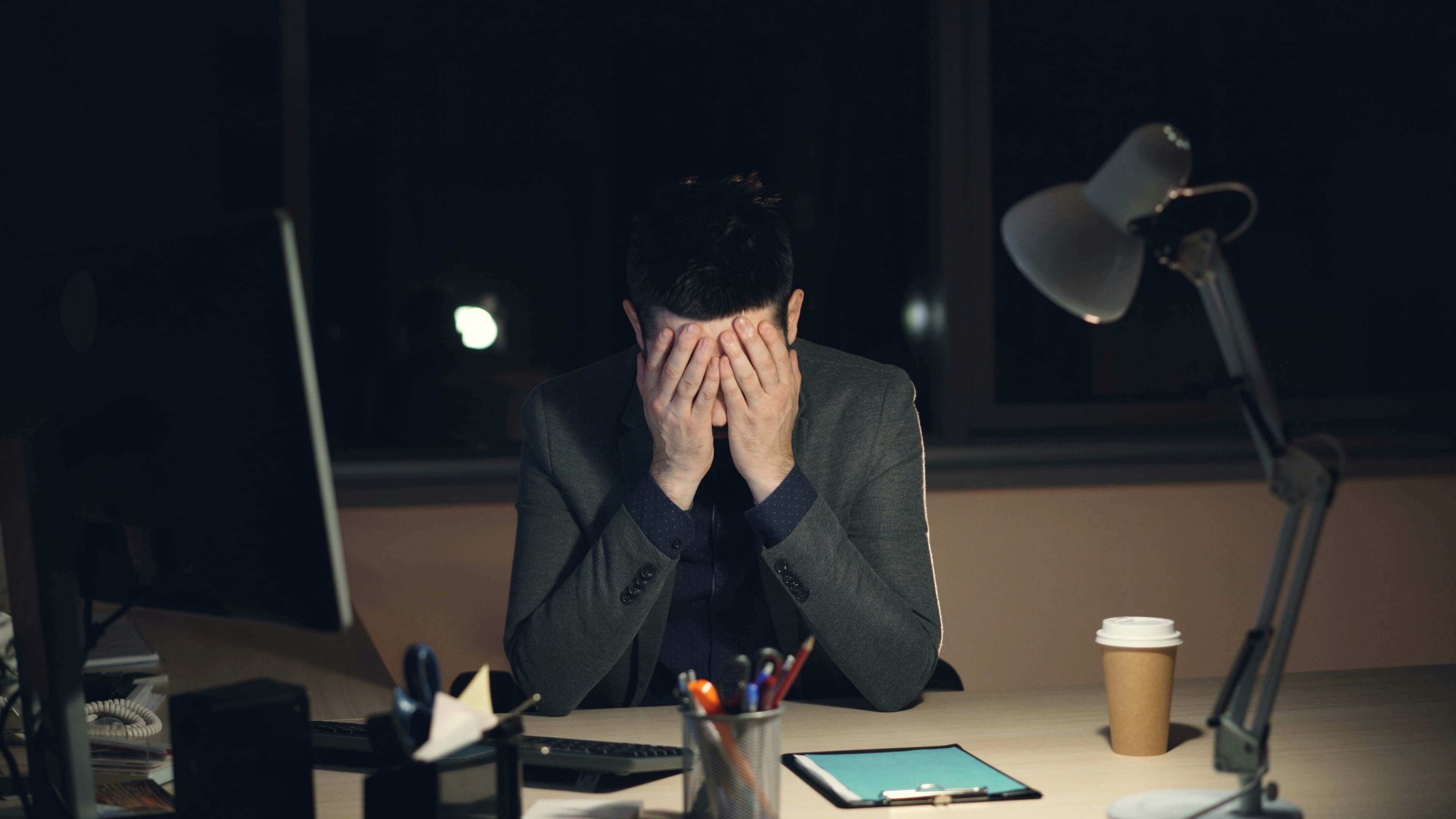 Man head in hands at his desk after business loss
