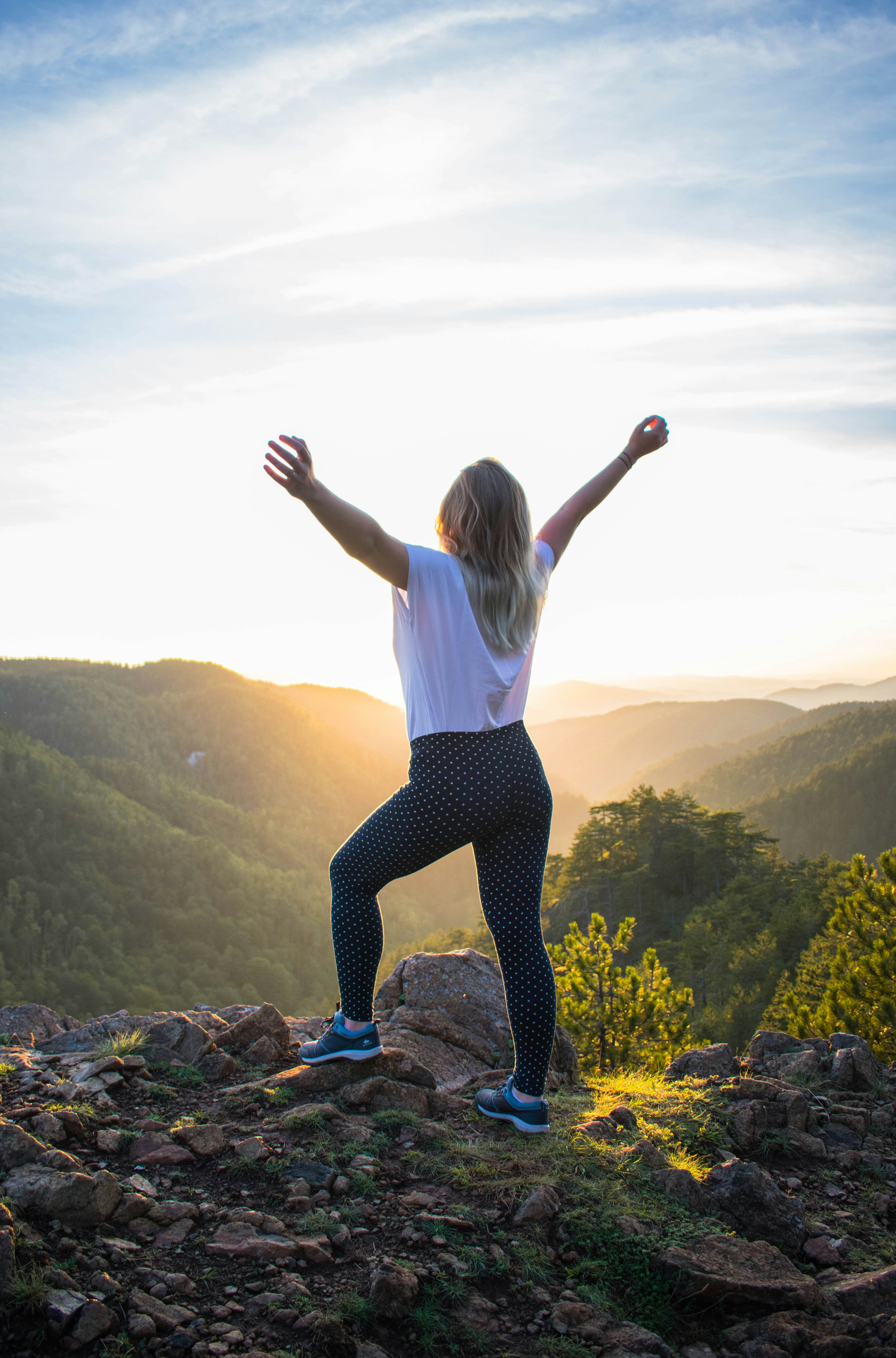 Woman arms raised in triumph at sunrise
