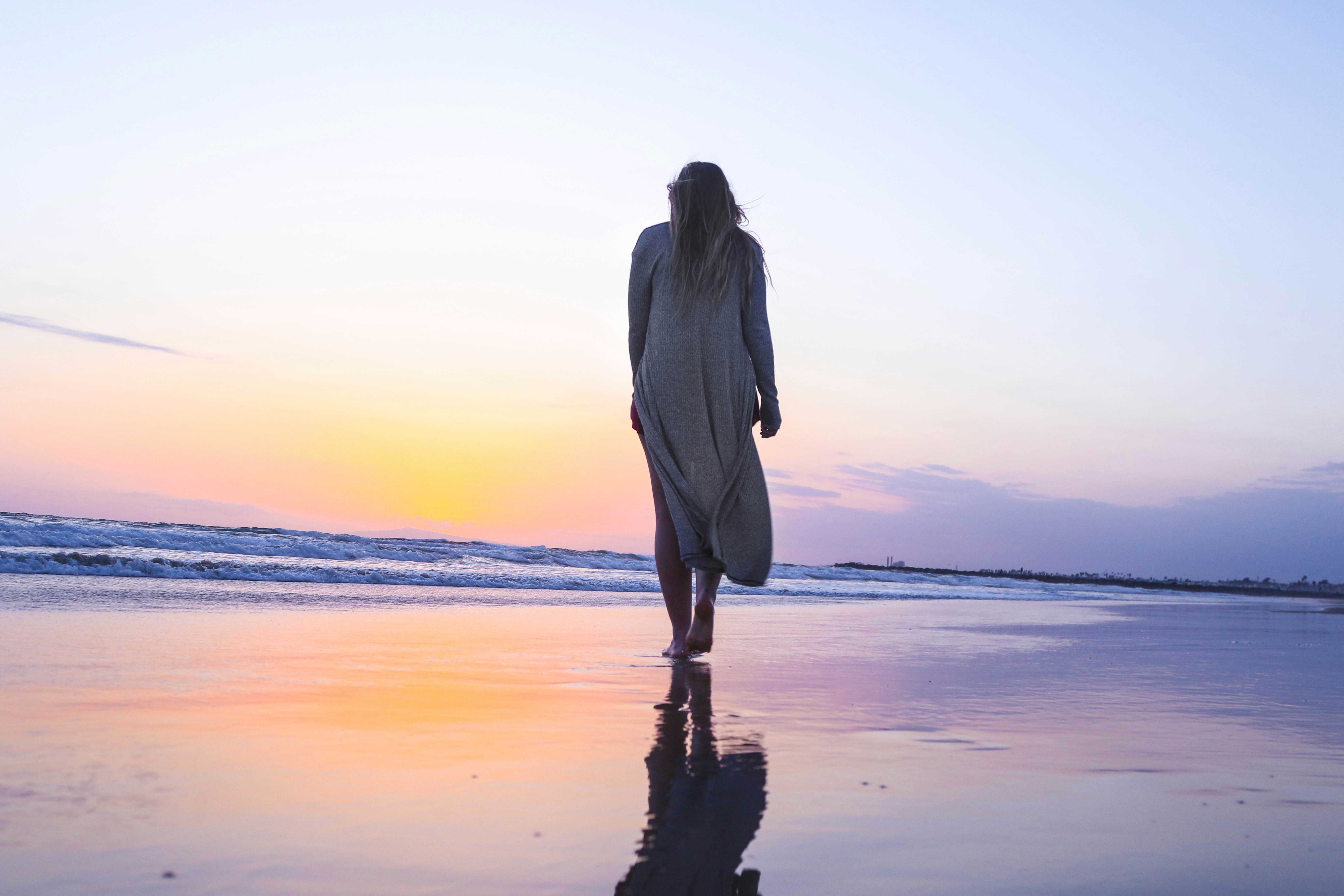 Woman walking alone toward the horizon at sunset with courage