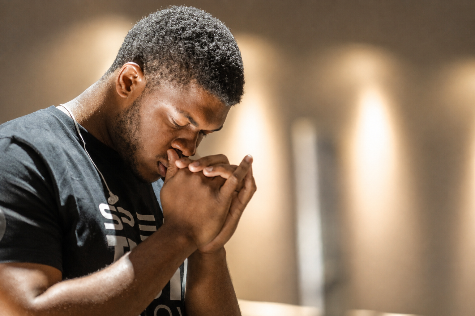 Man in quiet prayer, hands raised to his face seeking direction