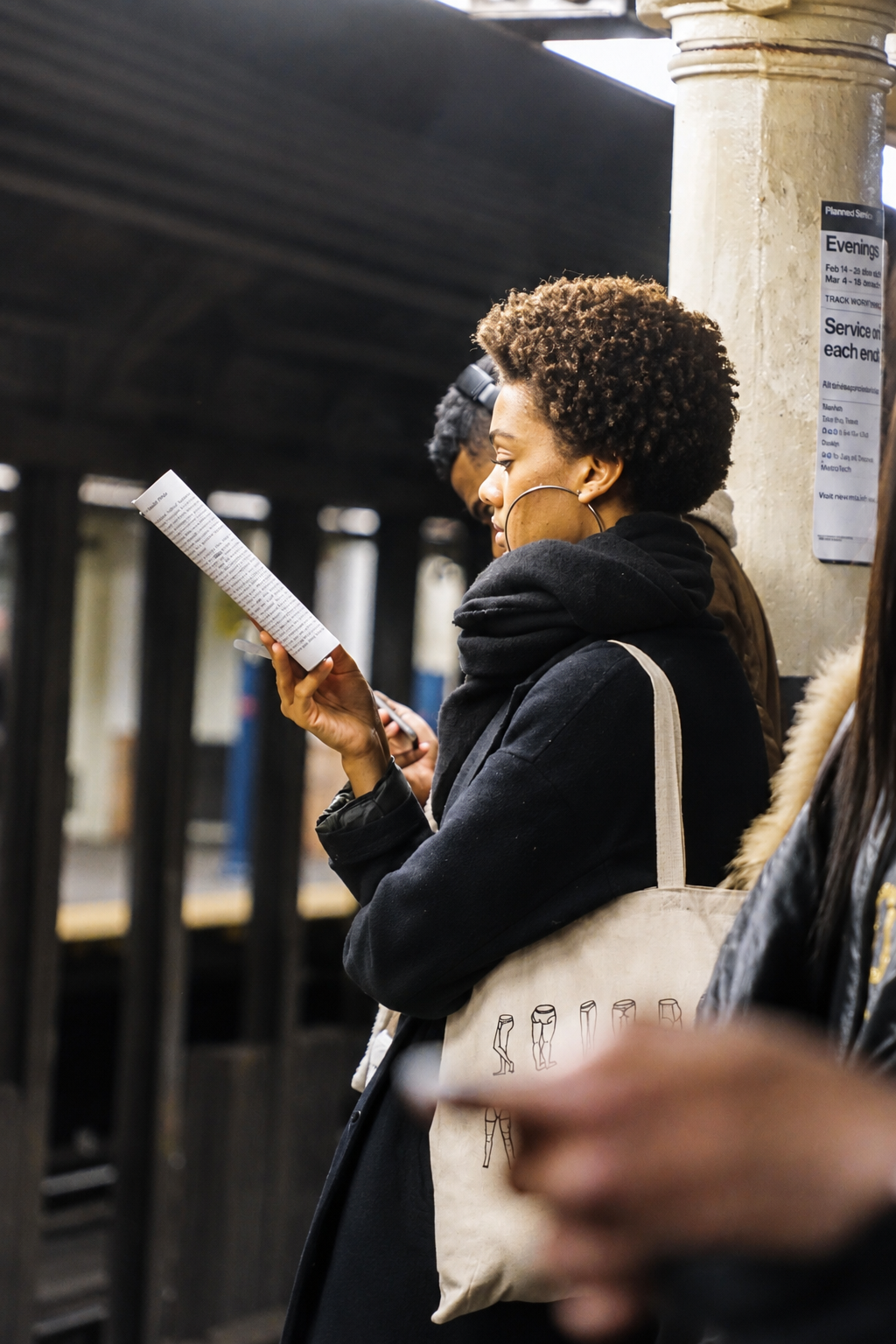 Woman absorbed in reading at a train station